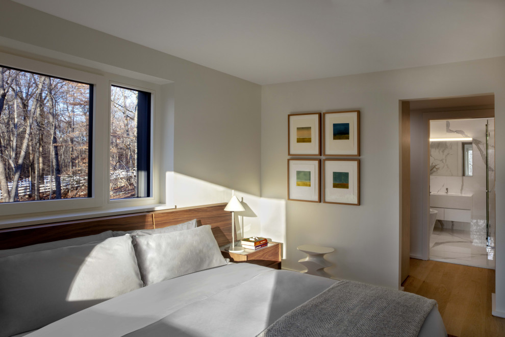 Mittelgroßes Modernes Hauptschlafzimmer mit weißer Wandfarbe, hellem Holzboden und freigelegten Dachbalken in New York