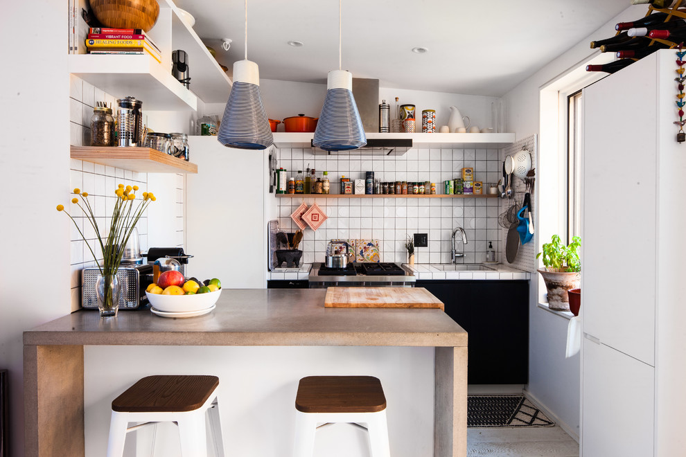 Inspiration for a small beach style single-wall kitchen in New York with a single-bowl sink, flat-panel cabinets, white cabinets, concrete benchtops, white splashback, ceramic splashback and a peninsula.