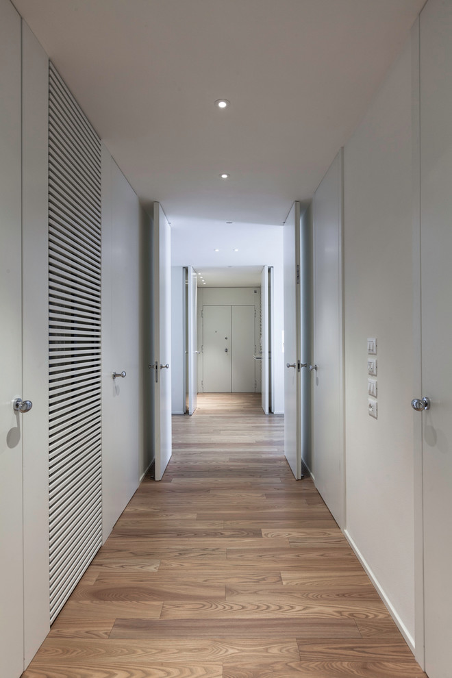 This is an example of a modern hallway in Bologna with white walls and light hardwood floors.