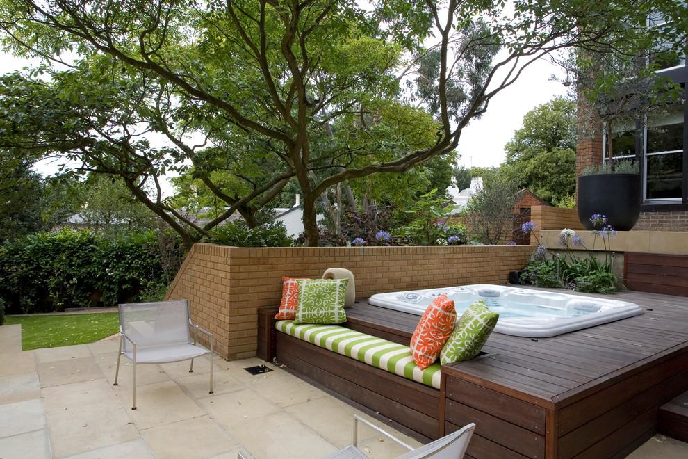 Design ideas for a mid-sized contemporary backyard pool in London with a hot tub and decking.