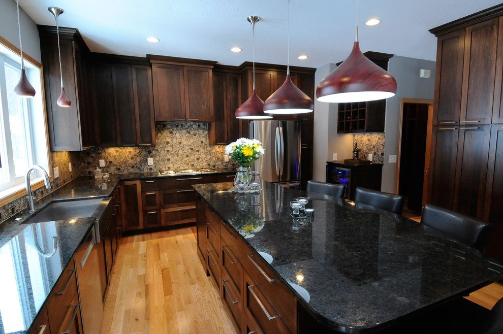 Large traditional l-shaped eat-in kitchen in Minneapolis with an undermount sink, shaker cabinets, dark wood cabinets, granite benchtops, multi-coloured splashback, mosaic tile splashback, stainless steel appliances, with island and medium hardwood floors.