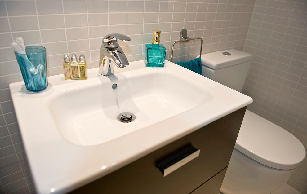 Ejemplo de aseo tradicional renovado pequeño con armarios tipo mueble, puertas de armario de madera en tonos medios, sanitario de pared, baldosas y/o azulejos grises, baldosas y/o azulejos de cerámica, paredes grises, suelo de baldosas de cerámica y lavabo encastrado