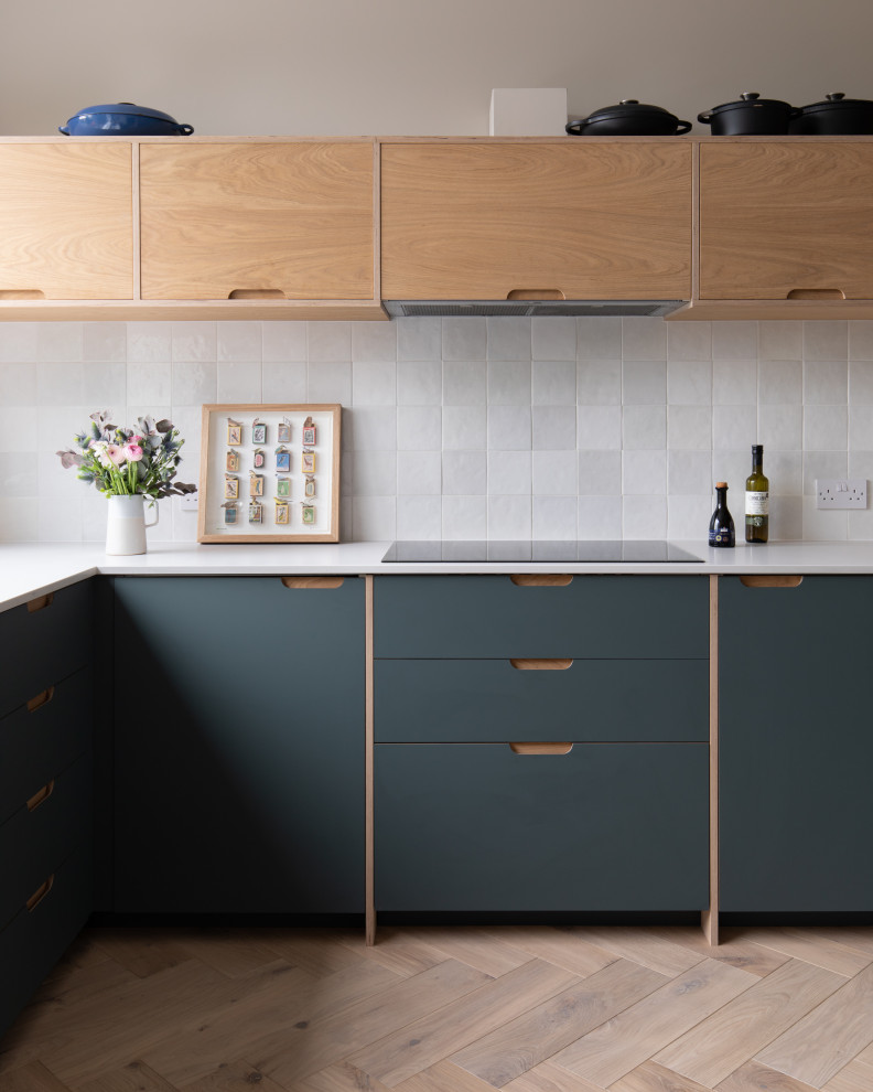 Inspiration for a mid-sized contemporary u-shaped separate kitchen in London with a drop-in sink, flat-panel cabinets, green cabinets, quartzite benchtops, white splashback, ceramic splashback, white appliances, light hardwood floors, no island, beige floor and white benchtop.