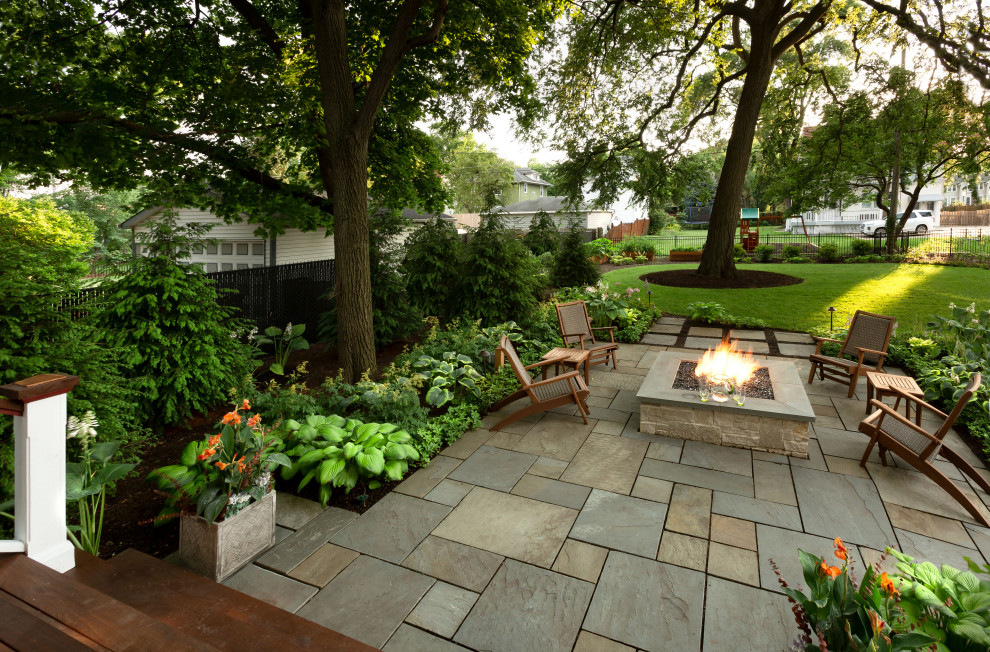 Photo of a large traditional backyard shaded garden for summer in Chicago with a fire feature and natural stone pavers.