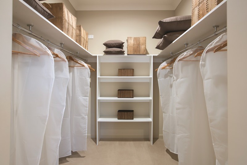Photo of a mid-sized tropical gender-neutral walk-in wardrobe in Melbourne with white cabinets and light hardwood floors.