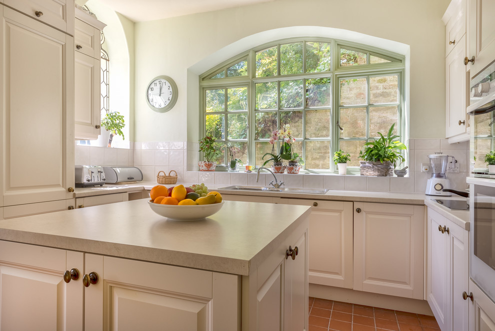 Design ideas for a mid-sized traditional u-shaped separate kitchen in Devon with a drop-in sink, recessed-panel cabinets, white cabinets, terra-cotta floors and with island.