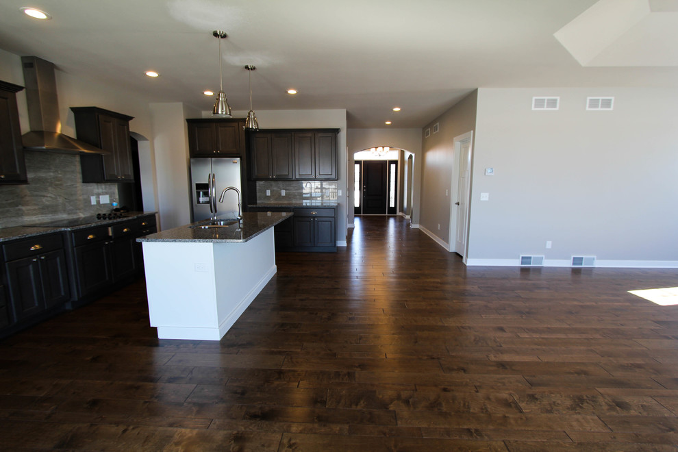 Inspiration for a transitional medium tone wood floor eat-in kitchen remodel with a double-bowl sink, gray cabinets, gray backsplash, porcelain backsplash, stainless steel appliances and an island