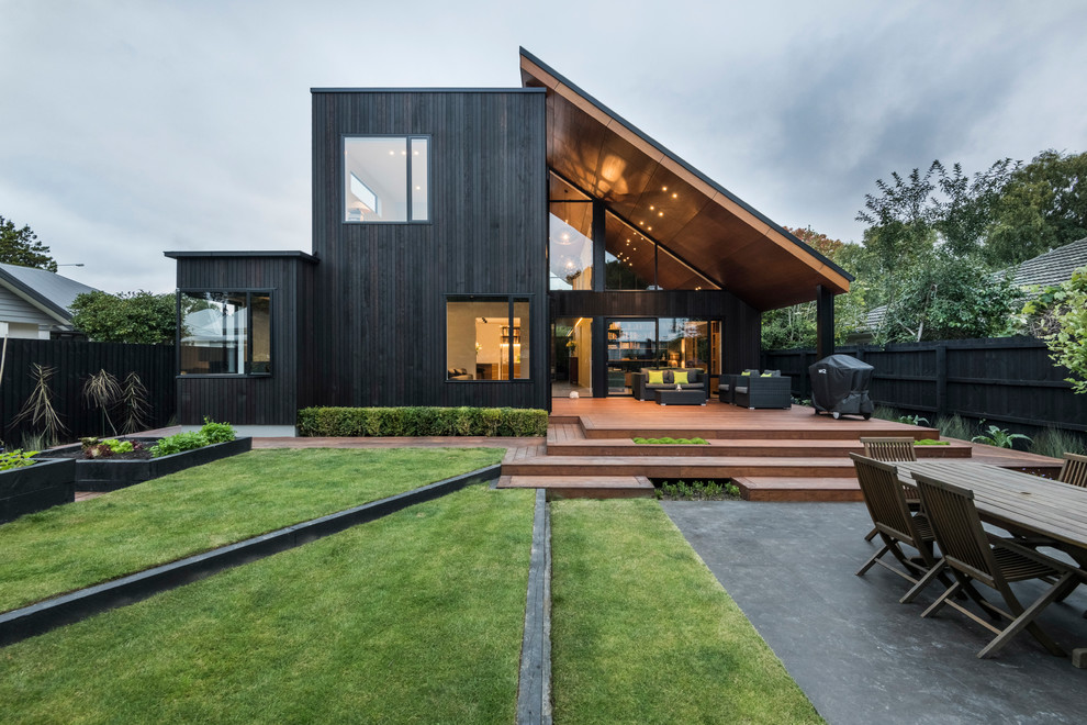Inspiration for a contemporary two-storey black house exterior in Christchurch with wood siding and a shed roof.