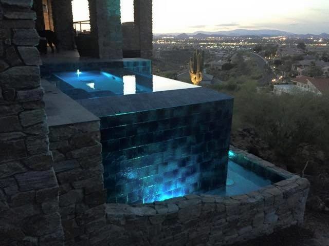 This is an example of a mid-sized transitional side yard infinity pool in Phoenix with a hot tub.