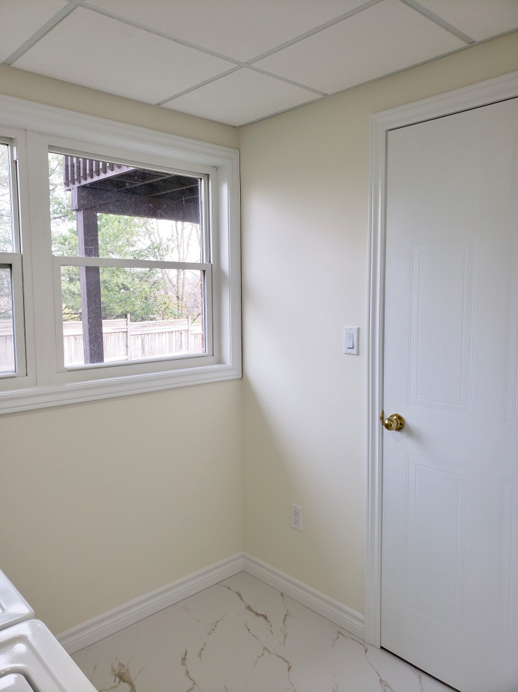 Example of a transitional porcelain tile and white floor laundry room design with an utility sink, shaker cabinets, white cabinets, white walls and a side-by-side washer/dryer
