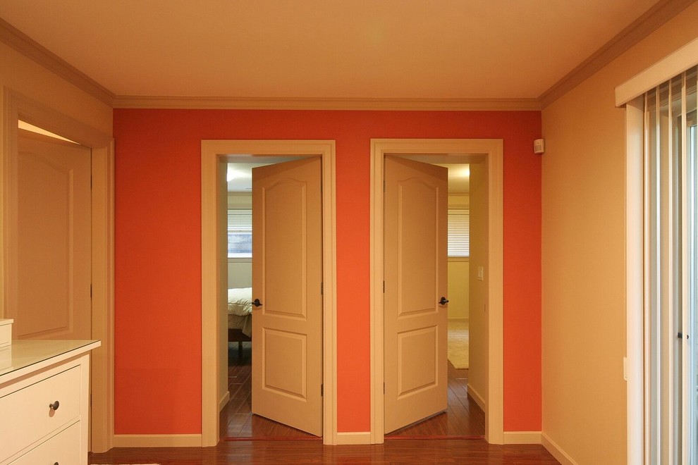Basement - mid-sized transitional underground medium tone wood floor and brown floor basement idea in Vancouver with orange walls, a standard fireplace and a stone fireplace