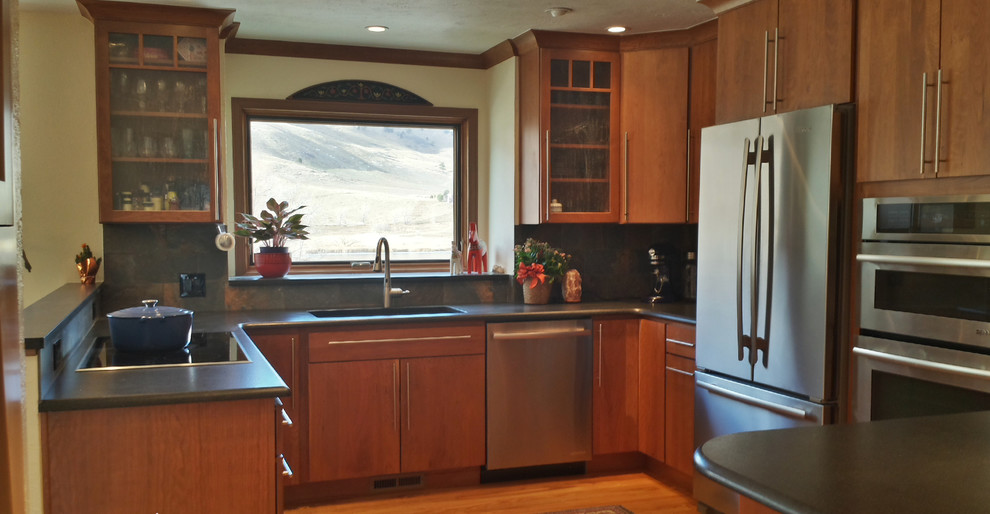 Photo of a kitchen in Denver with a triple-bowl sink, flat-panel cabinets, medium wood cabinets, stainless steel appliances and light hardwood floors.