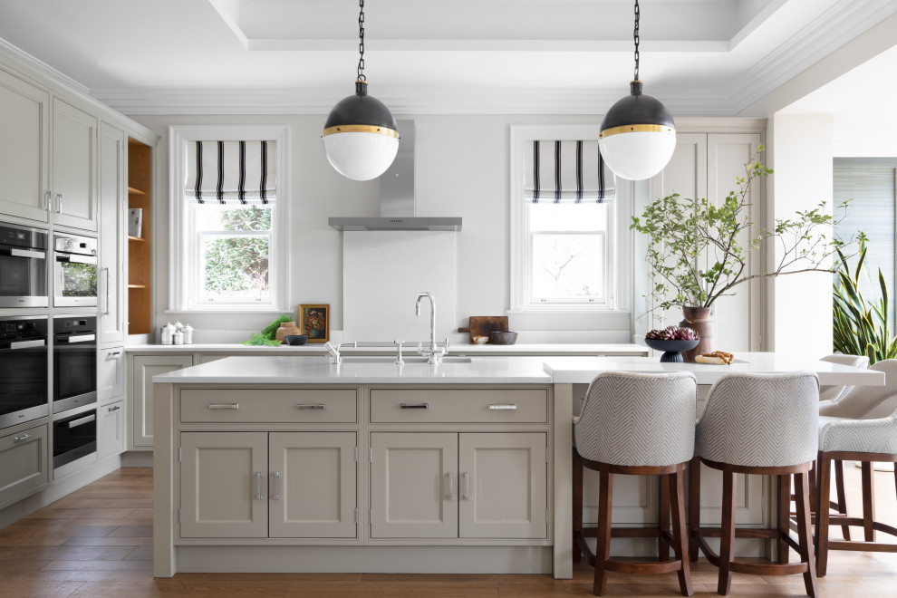 Design ideas for a large transitional l-shaped open plan kitchen in Cheshire with shaker cabinets, grey cabinets, quartz benchtops, white splashback, engineered quartz splashback, stainless steel appliances, porcelain floors, with island, brown floor, white benchtop and coffered.