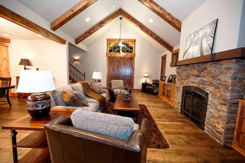 This is an example of a mid-sized country formal open concept living room in Seattle with white walls, dark hardwood floors, a standard fireplace, a stone fireplace surround and no tv.