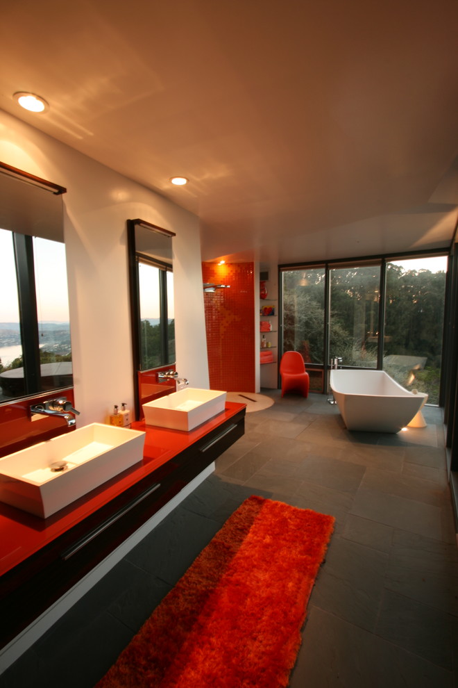 Large 1950s master orange tile and glass tile slate floor bathroom photo in San Francisco with a wall-mount sink, flat-panel cabinets, dark wood cabinets, glass countertops, a wall-mount toilet and white walls