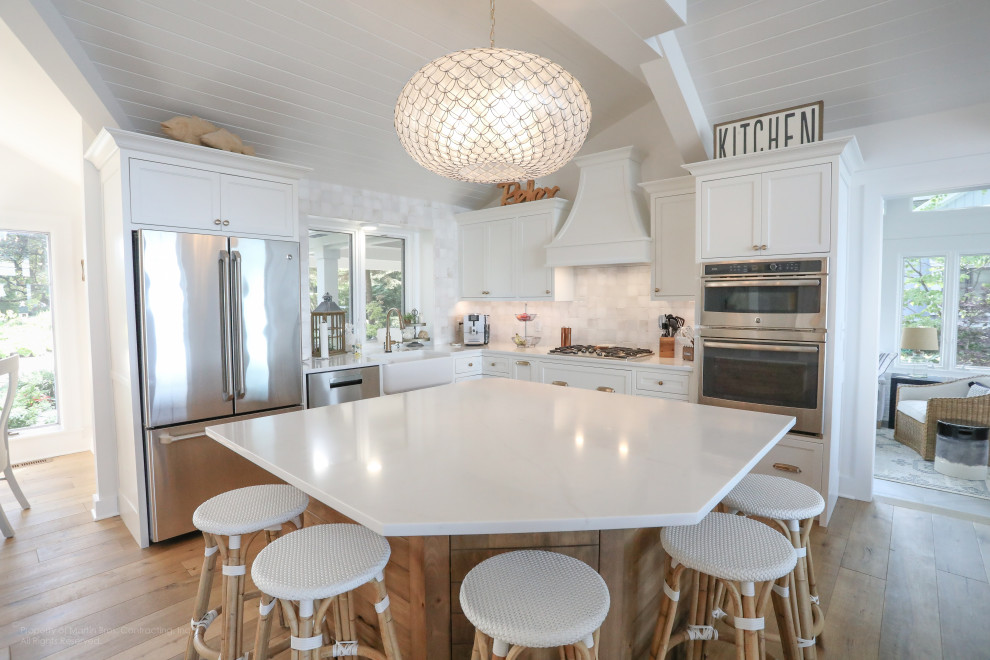 Exempel på ett mellanstort maritimt vit vitt kök, med en rustik diskho, luckor med profilerade fronter, vita skåp, bänkskiva i kvarts, vitt stänkskydd, stänkskydd i keramik, rostfria vitvaror, mellanmörkt trägolv och en köksö