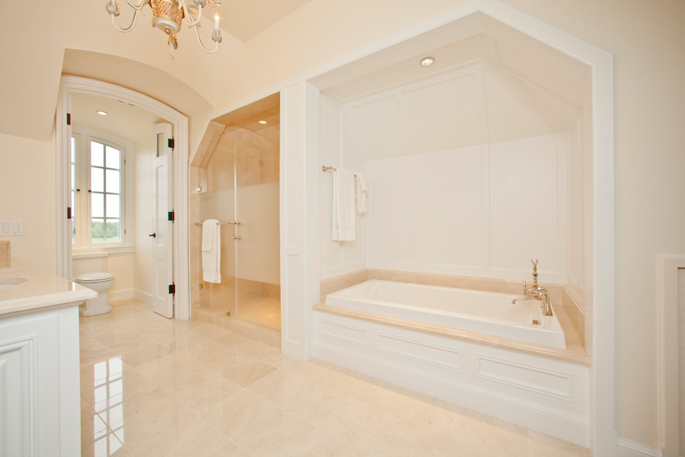 Mid-sized traditional master bathroom in Raleigh with a hinged shower door, raised-panel cabinets, white cabinets, a drop-in tub, an alcove shower, a two-piece toilet, white walls, porcelain floors, an undermount sink, engineered quartz benchtops and beige floor.