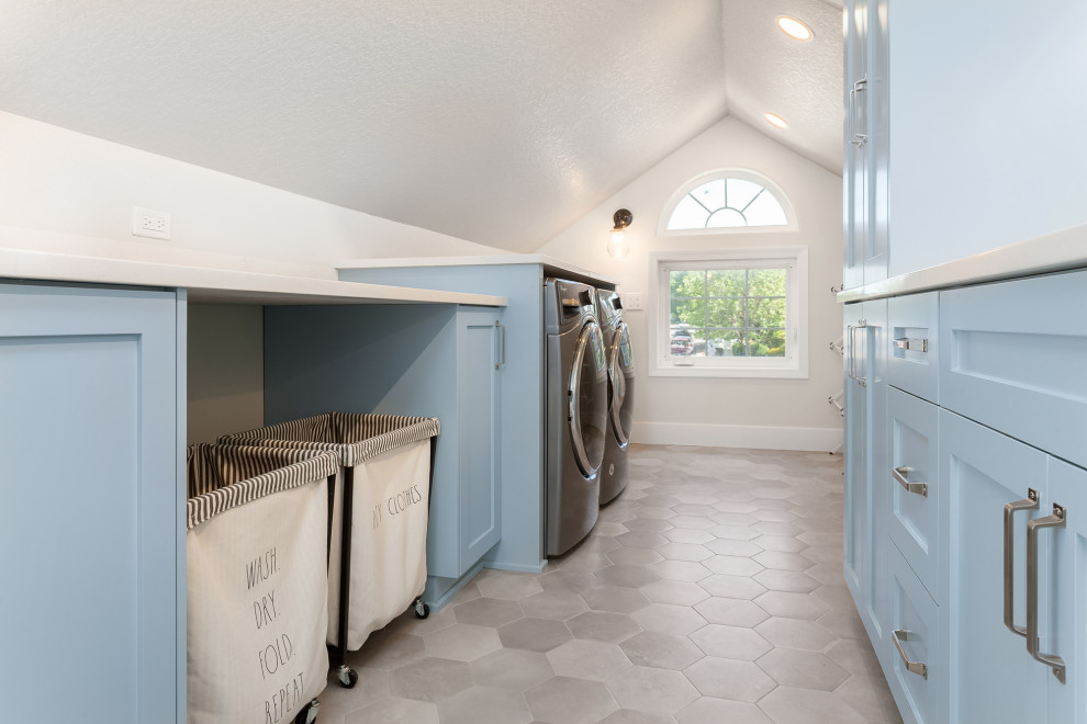 Inspiration for a country galley dedicated laundry room in Portland with an undermount sink, shaker cabinets, blue cabinets, quartz benchtops, white splashback, ceramic splashback, white walls, porcelain floors, a side-by-side washer and dryer, grey floor, white benchtop and vaulted.