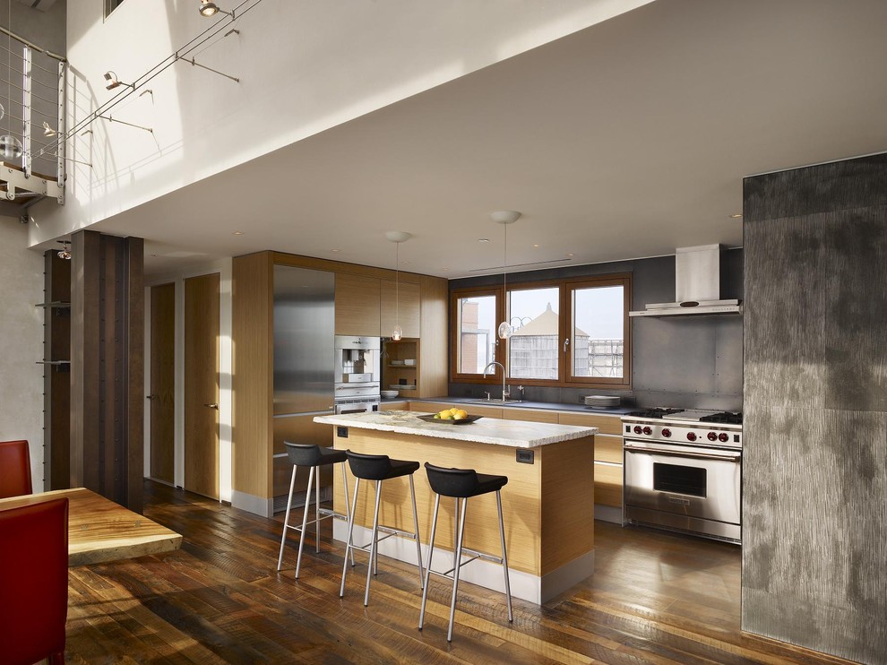 Photo of a contemporary l-shaped kitchen in New York with flat-panel cabinets, stainless steel appliances, light wood cabinets and grey splashback.