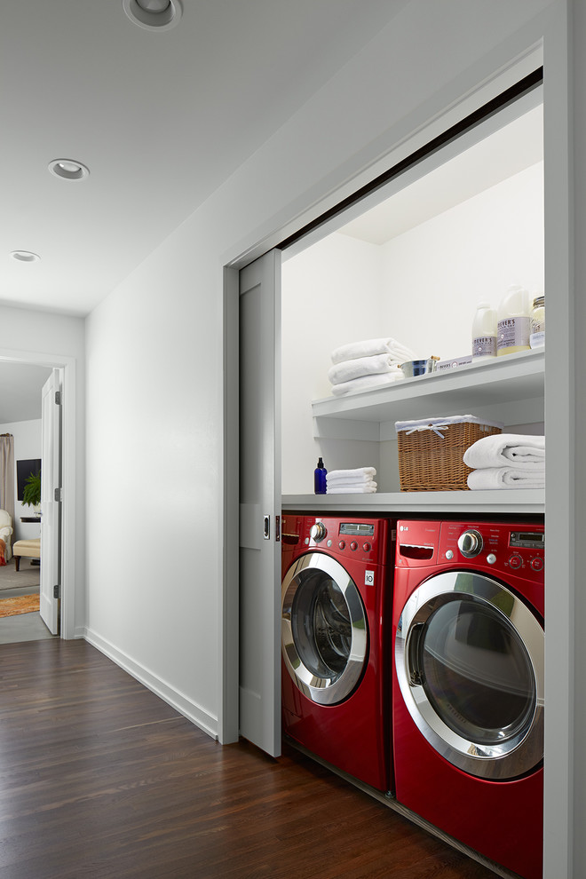 This is an example of a small transitional single-wall laundry cupboard in Minneapolis with open cabinets, white cabinets, wood benchtops, white walls, medium hardwood floors and a side-by-side washer and dryer.