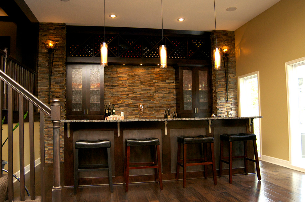 Inspiration for a large modern single-wall seated home bar in Kansas City with an undermount sink, flat-panel cabinets, dark wood cabinets, granite benchtops, brown splashback, stone tile splashback, dark hardwood floors, brown floor and grey benchtop.