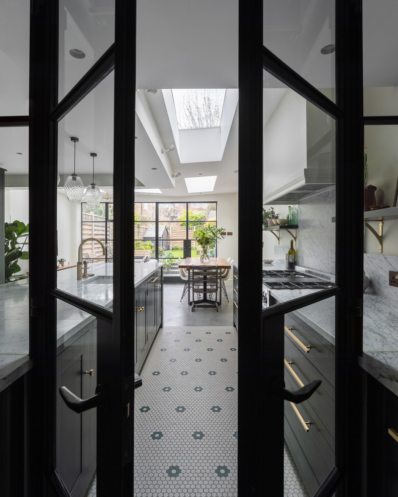 This is an example of a mid-sized contemporary u-shaped eat-in kitchen in London with an integrated sink, shaker cabinets, green cabinets, marble benchtops, white splashback, marble splashback, stainless steel appliances, concrete floors, with island, grey floor and white benchtop.