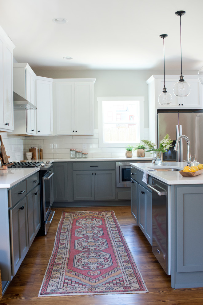 Example of a transitional l-shaped kitchen design with stainless steel appliances and an island