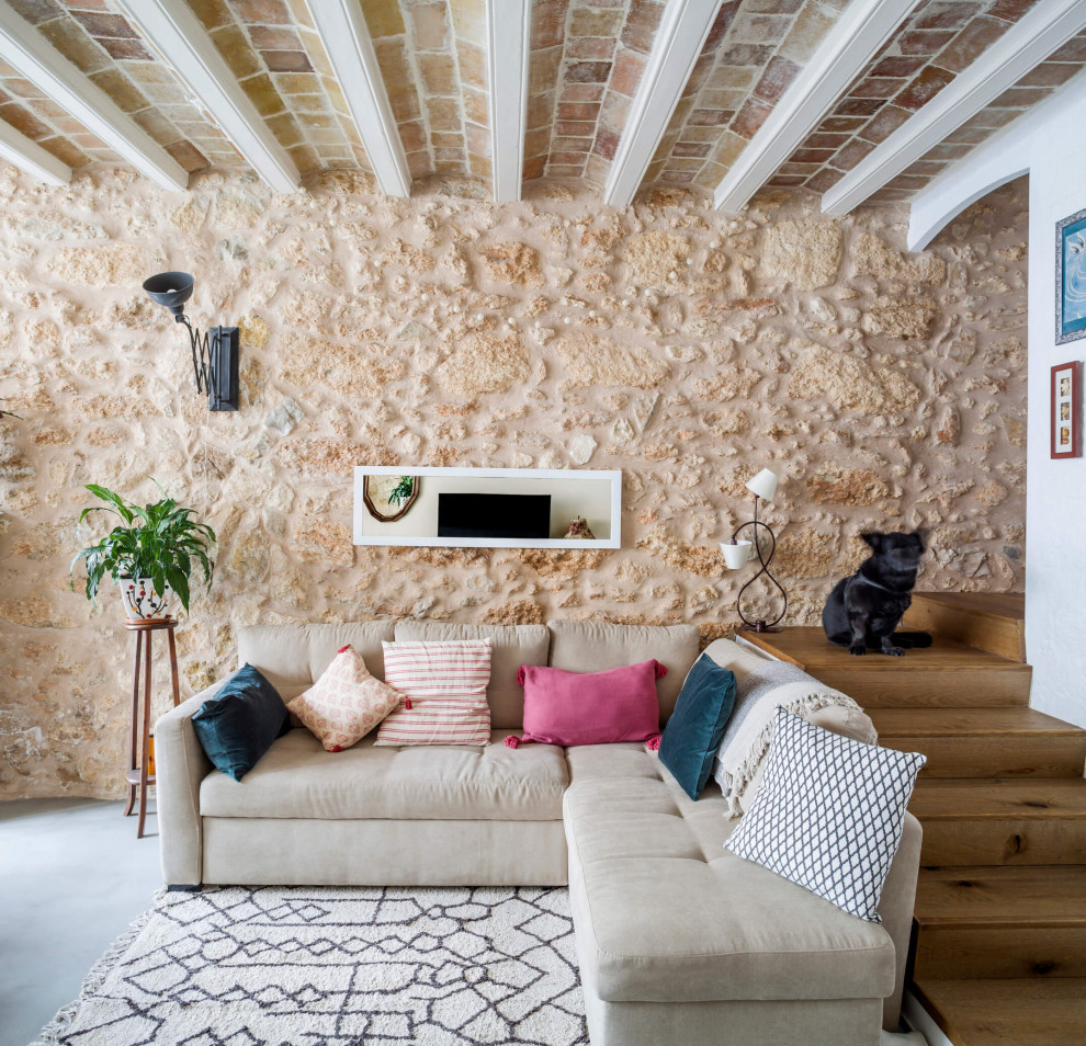 Aménagement d'un petit salon bord de mer ouvert avec un téléviseur fixé au mur, sol en béton ciré, un sol gris, poutres apparentes et un mur en parement de brique.
