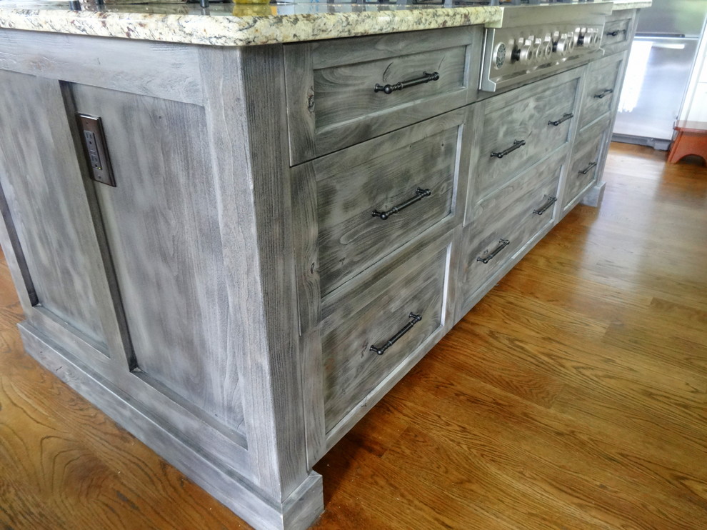 Mid-sized transitional l-shaped medium tone wood floor open concept kitchen photo in Charlotte with a farmhouse sink, shaker cabinets, white cabinets, granite countertops, beige backsplash, subway tile backsplash, stainless steel appliances and an island