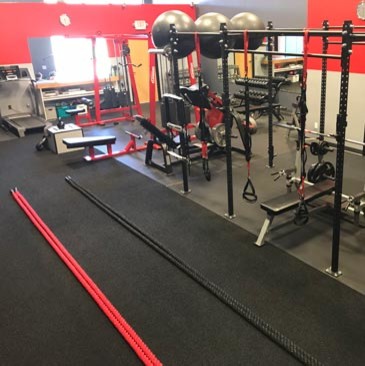 This is an example of a large home weight room in Minneapolis with red walls and black floor.