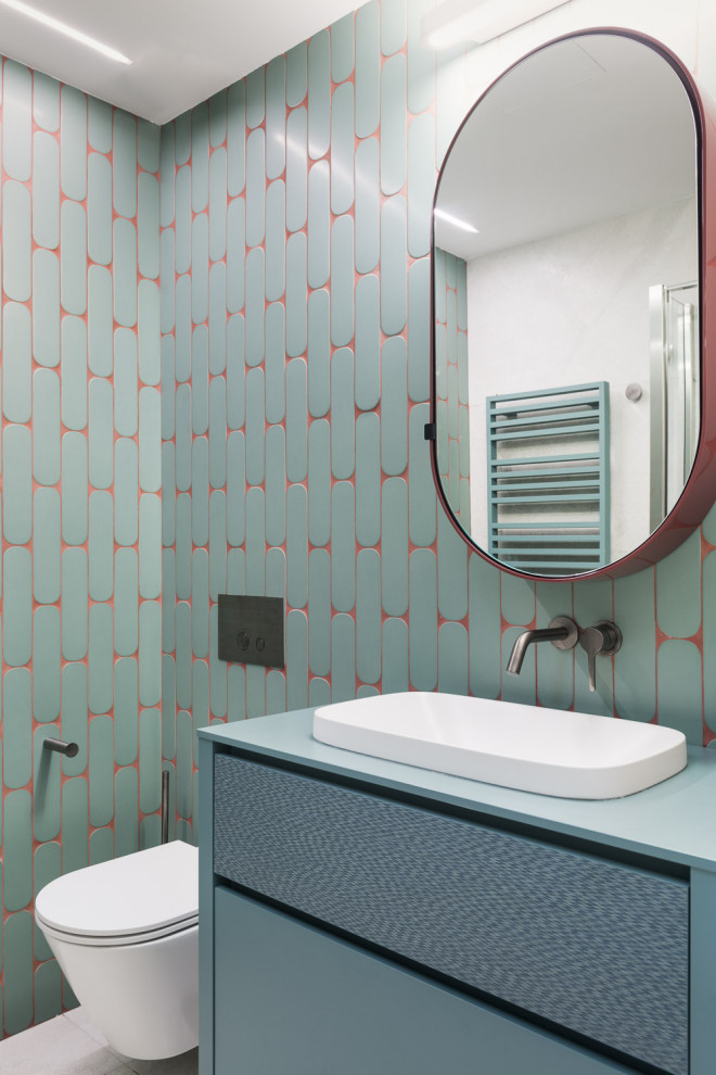 Foto på ett litet funkis turkos badrum, med släta luckor, gröna skåp, en vägghängd toalettstol, grön kakel, keramikplattor, gröna väggar, klinkergolv i porslin, ett nedsänkt handfat och grått golv