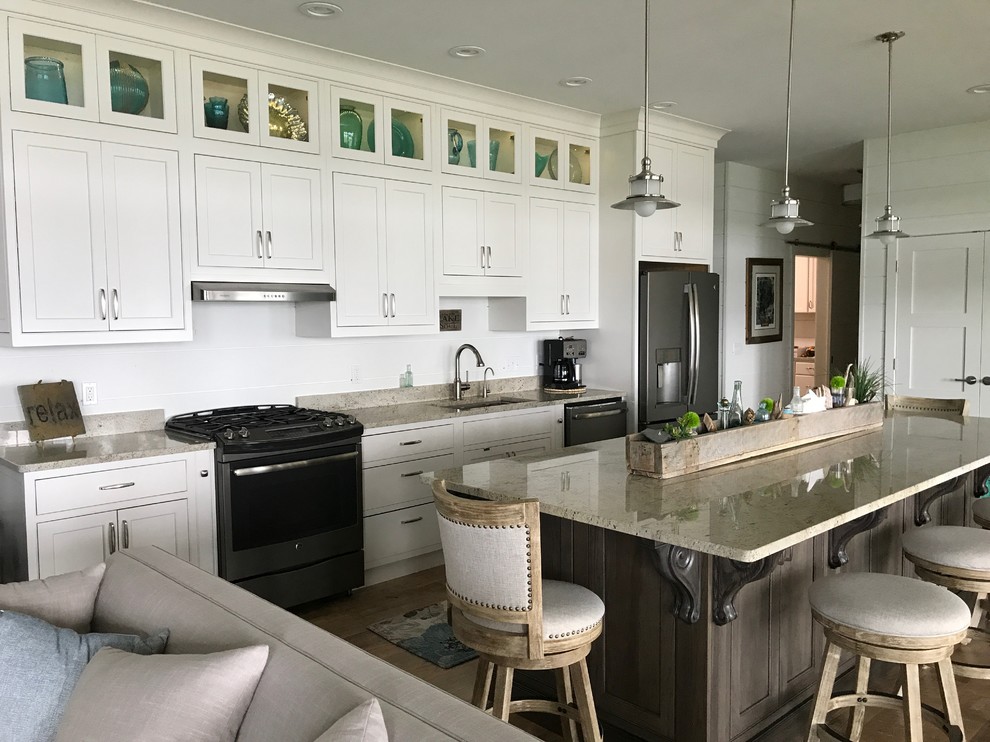 Large beach style single-wall eat-in kitchen in New York with an undermount sink, shaker cabinets, grey cabinets, stainless steel appliances, medium hardwood floors, with island, brown floor, onyx benchtops, white splashback, cement tile splashback and beige benchtop.