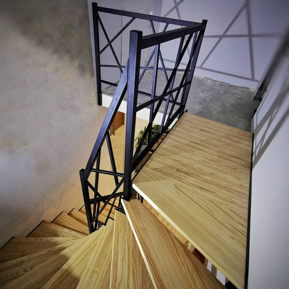 На фото: угловая деревянная лестница среднего размера в стиле лофт с деревянными ступенями и металлическими перилами с