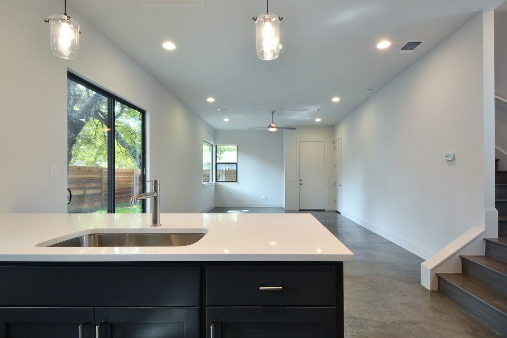 Minimalist galley concrete floor kitchen photo in Austin with quartz countertops, gray backsplash and an island