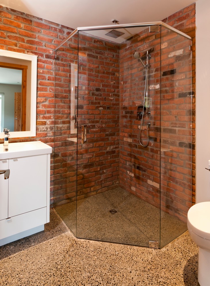 Photo of a large contemporary 3/4 bathroom in Vancouver with flat-panel cabinets, white cabinets, a corner shower, a one-piece toilet, an integrated sink, red walls and concrete floors.