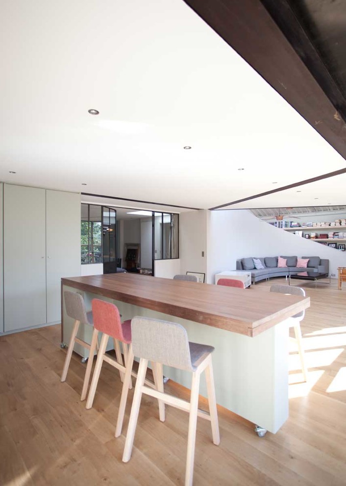 This is an example of a mid-sized contemporary kitchen/dining combo in Paris with white walls, light hardwood floors and beige floor.