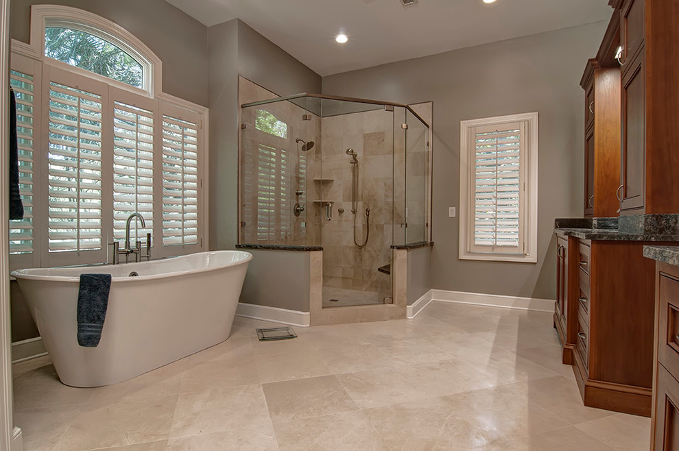 Photo of a mediterranean master bathroom in Charleston with recessed-panel cabinets, medium wood cabinets, a freestanding tub, a corner shower, beige tile and beige walls.