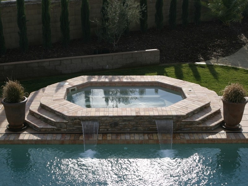 Example of a backyard stone and custom-shaped hot tub design