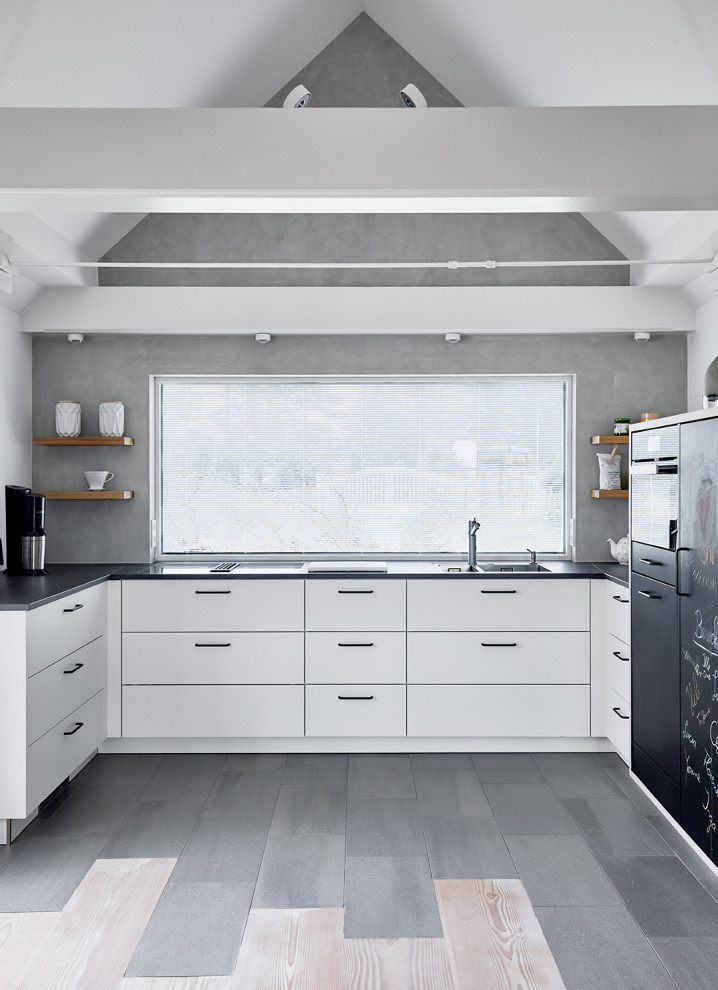 Mid-sized contemporary u-shaped kitchen in Other with an integrated sink, flat-panel cabinets, white cabinets, grey splashback, panelled appliances, no island, grey floor and black benchtop.