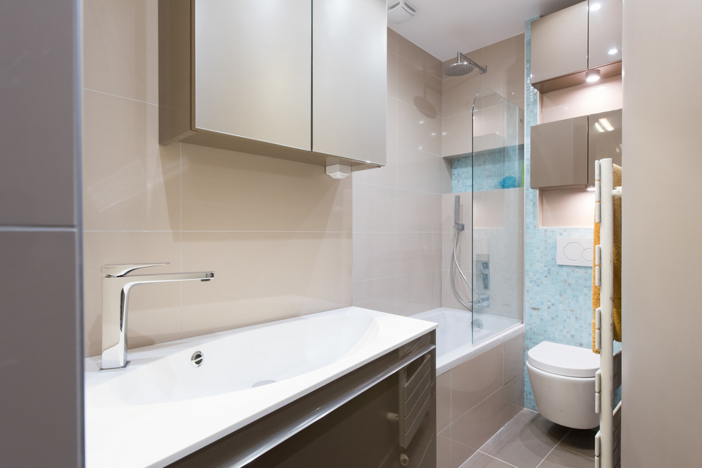 Small modern master bathroom in Paris with a drop-in sink, flat-panel cabinets, brown cabinets, solid surface benchtops, an undermount tub, a shower/bathtub combo, a wall-mount toilet, beige tile, terra-cotta tile, brown walls and terra-cotta floors.