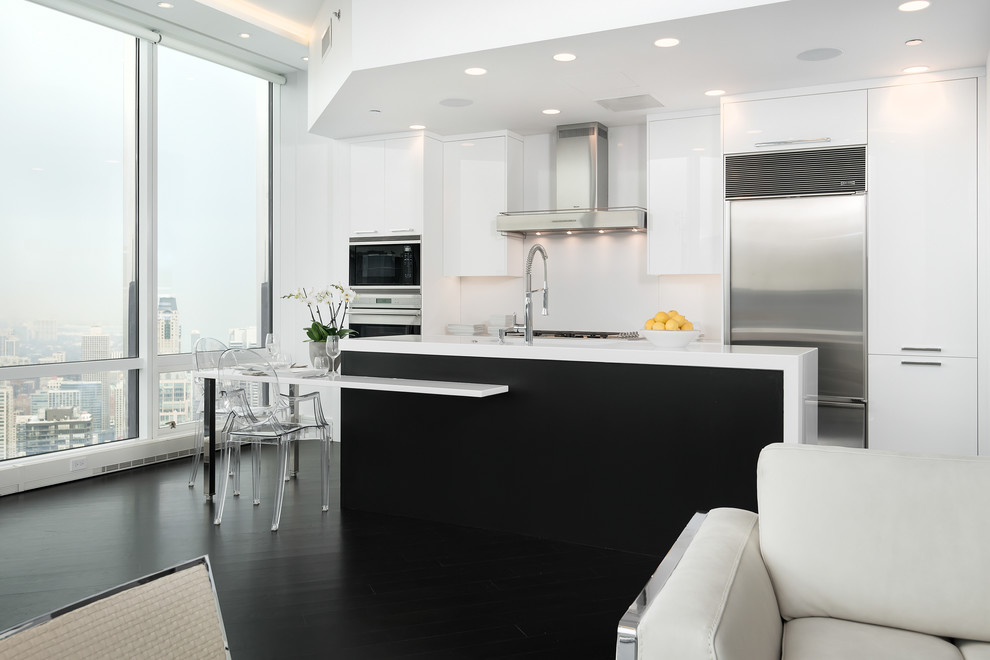 Small contemporary galley open plan kitchen in Chicago with an undermount sink, flat-panel cabinets, quartz benchtops, white splashback, stainless steel appliances, dark hardwood floors and with island.