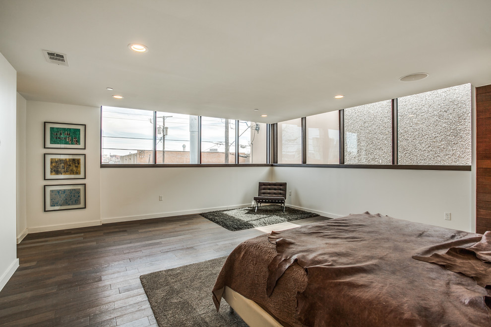 This is an example of a modern master bedroom in Dallas with dark hardwood floors.