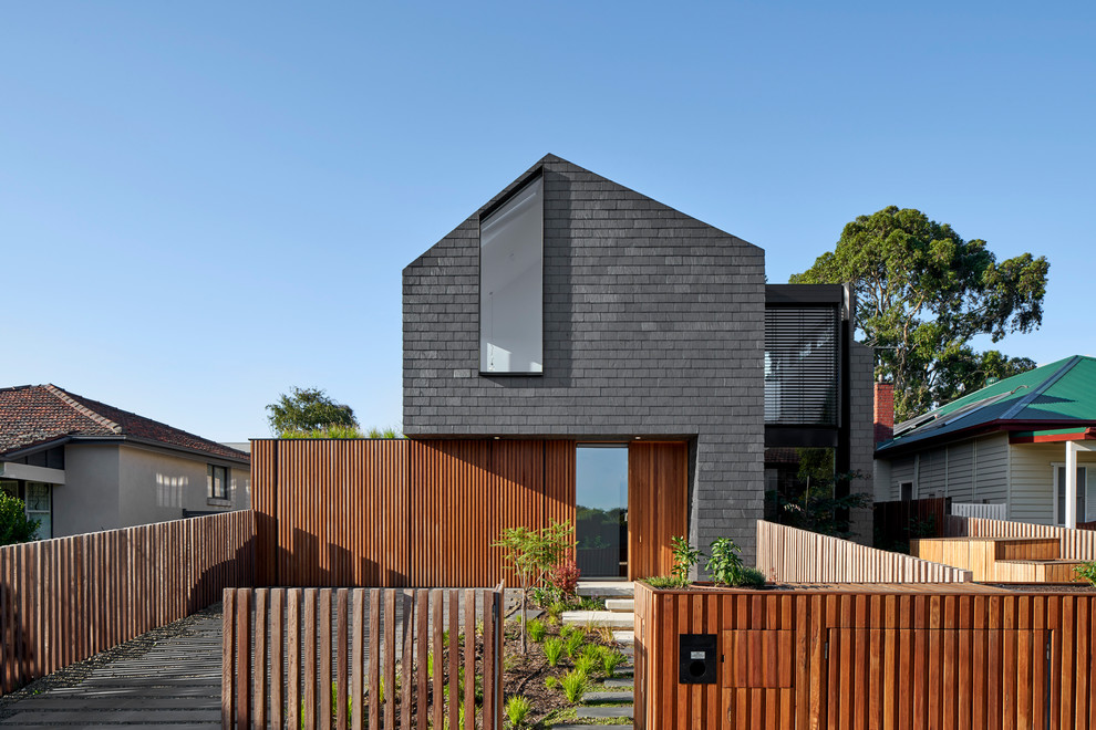 Contemporary black house exterior in Melbourne with wood siding, a gable roof and a shingle roof.