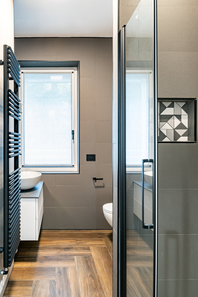 Inspiration for a small modern 3/4 bathroom in Milan with flat-panel cabinets, white cabinets, a curbless shower, a wall-mount toilet, beige tile, porcelain tile, white walls, porcelain floors, a vessel sink, granite benchtops, brown floor, a hinged shower door, black benchtops, a single vanity and a floating vanity.