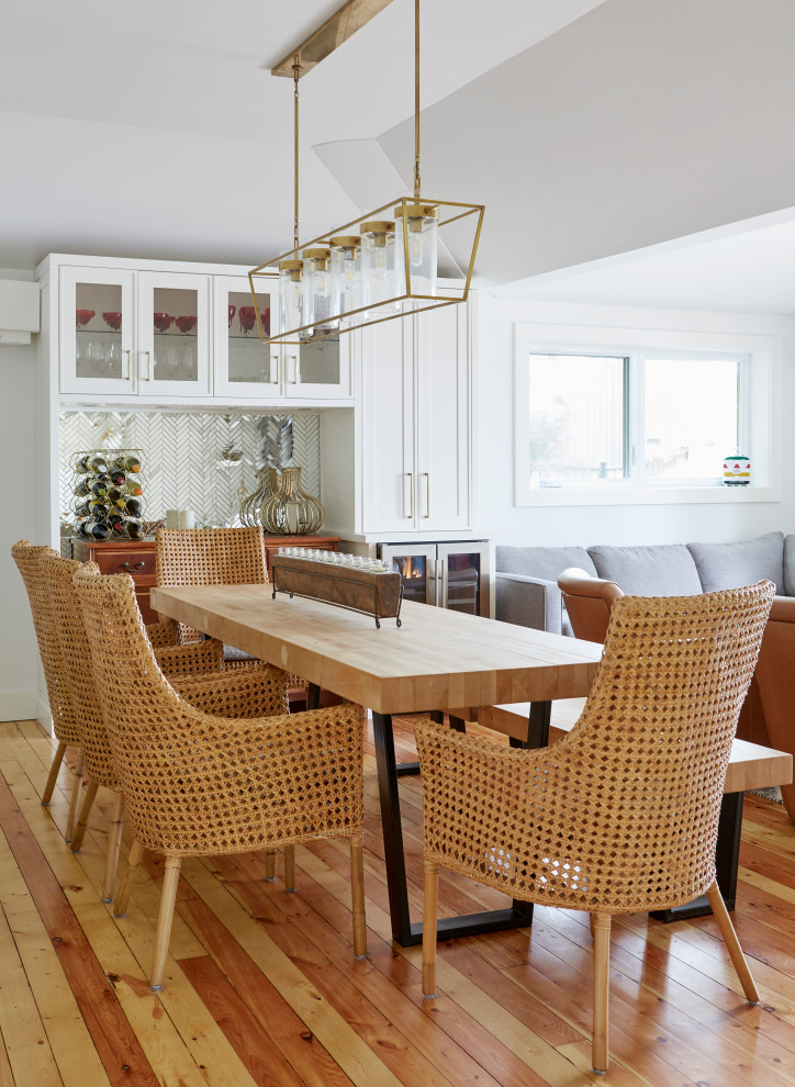 This is an example of a small country open plan dining room in Toronto with white walls, light hardwood flooring and a vaulted ceiling.