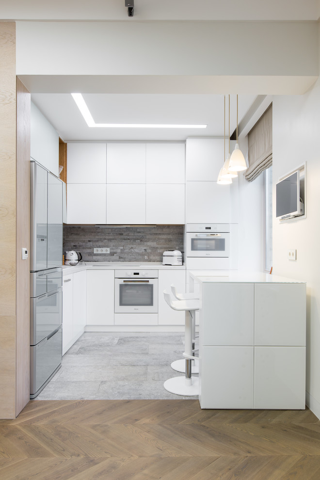 Inspiration for a mid-sized scandinavian l-shaped open plan kitchen in Moscow with flat-panel cabinets, white cabinets, quartz benchtops, grey splashback, porcelain splashback, white appliances, porcelain floors and no island.