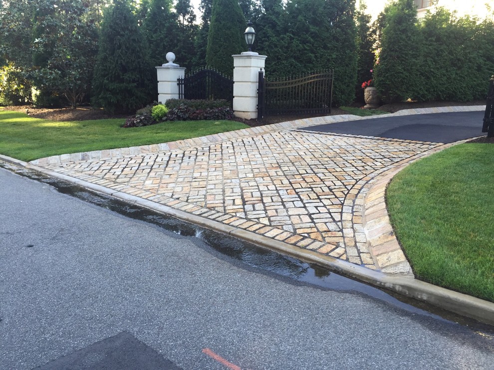 This is an example of a large mediterranean front yard driveway in New York with a garden path and natural stone pavers.