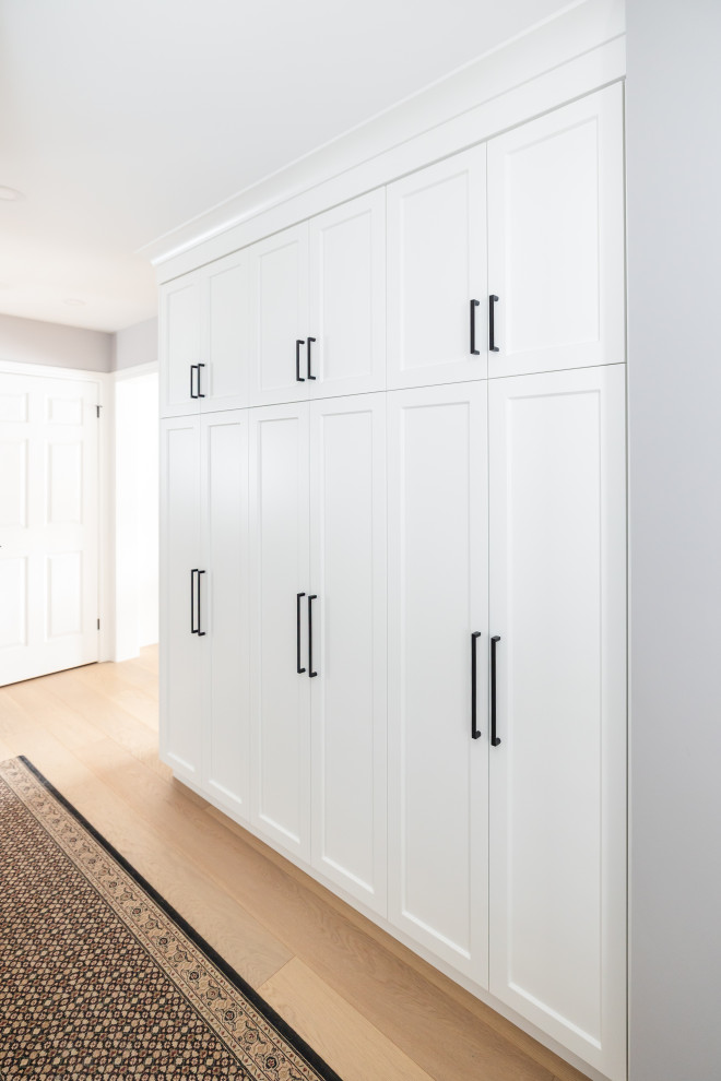 Mid-sized transitional u-shaped light wood floor eat-in kitchen photo in Toronto with an undermount sink, shaker cabinets, white cabinets, quartz countertops, white backsplash, quartz backsplash, stainless steel appliances, an island and white countertops