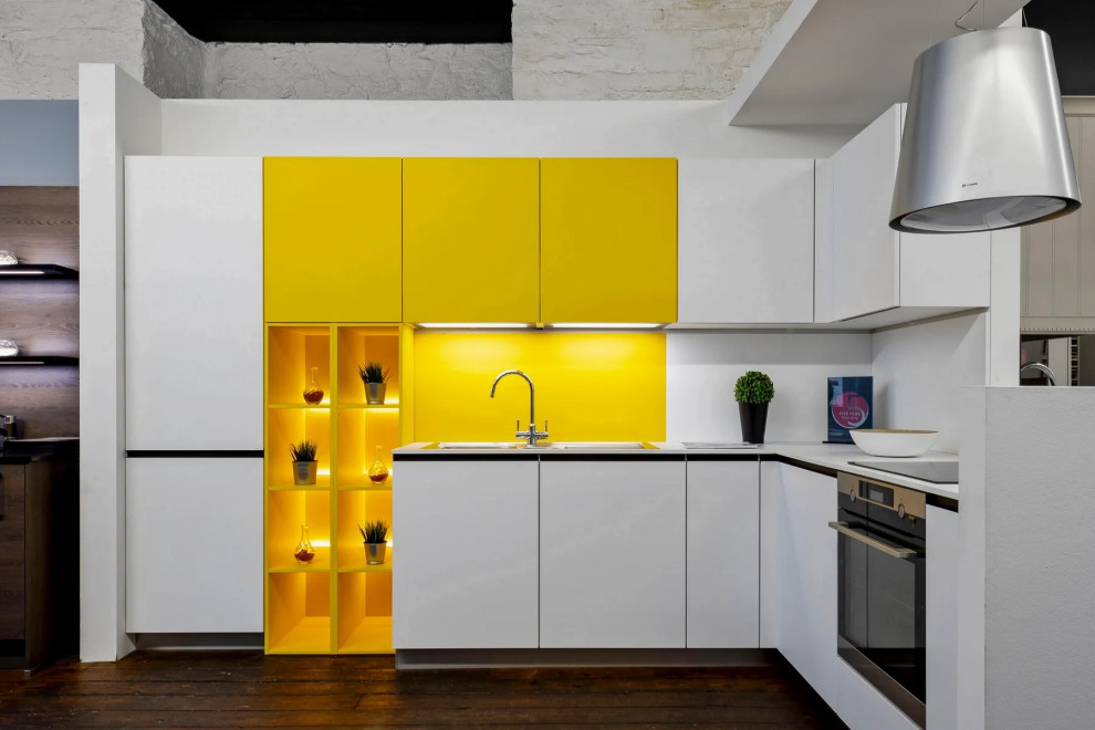 Photo of a small l-shaped enclosed kitchen with a built-in sink, flat-panel cabinets, white cabinets, laminate countertops, yellow splashback, metal splashback, stainless steel appliances, dark hardwood flooring, no island, brown floors and white worktops.