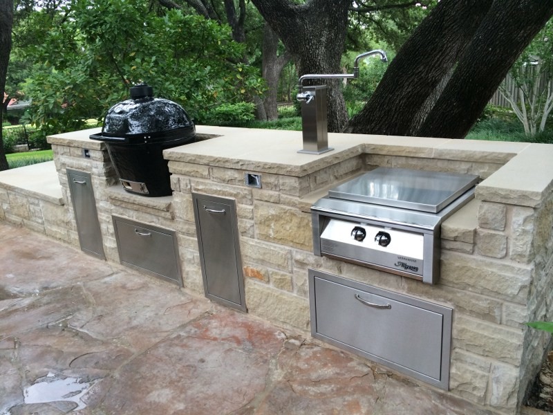 Photo of a mid-sized traditional backyard patio with an outdoor kitchen, stamped concrete and a roof extension.